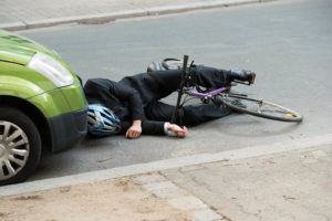 cyclist laying on the road in front a car after a collision