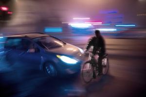 guy riding bike in front of car