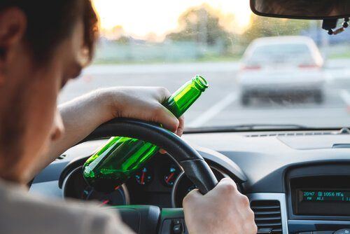 Drunk driver holding a bottle of alcohol