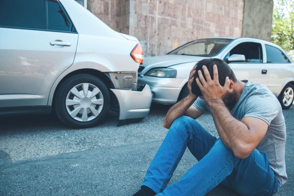 Un hombre se sienta en la calle después de un accidente de auto.